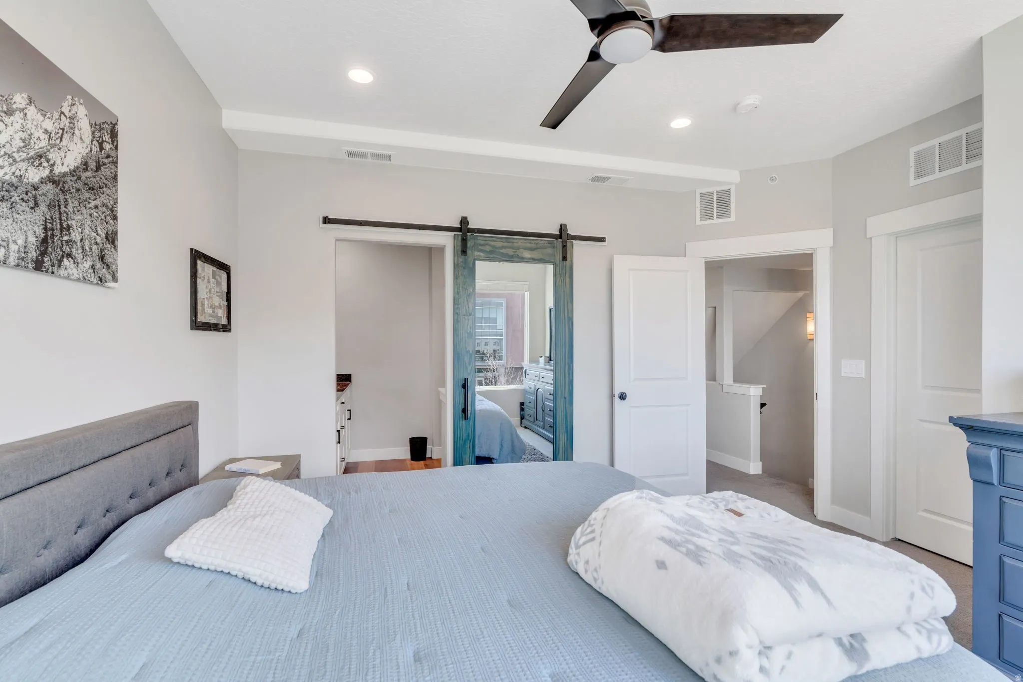 Carpeted bedroom featuring a barn door, connected bathroom, recessed lighting, and ceiling fan