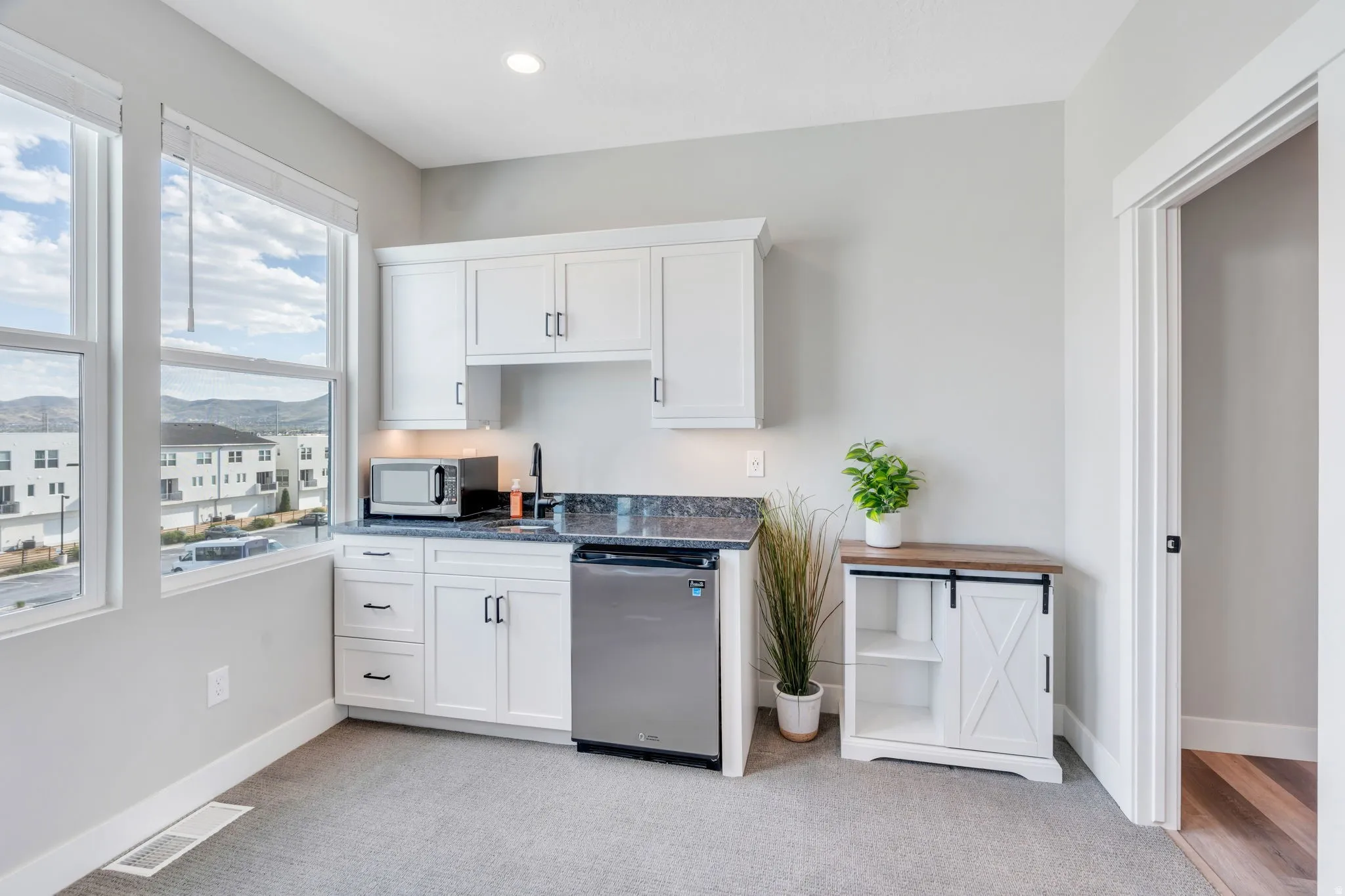 Kitchen featuring white cabinets, light colored carpet, stainless steel appliances, a mountain view, and recessed lighting