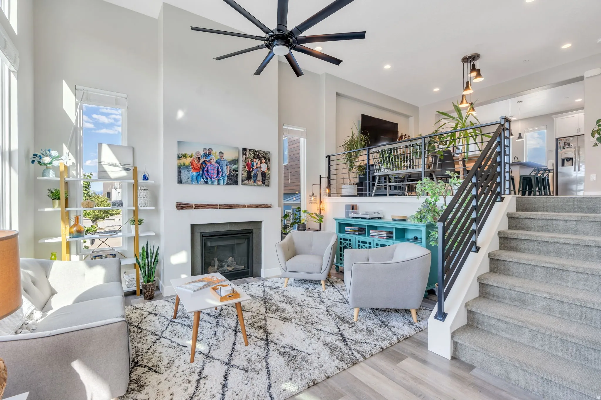 Living room with a glass covered fireplace, a high ceiling, wood finished floors, ceiling fan, and recessed lighting