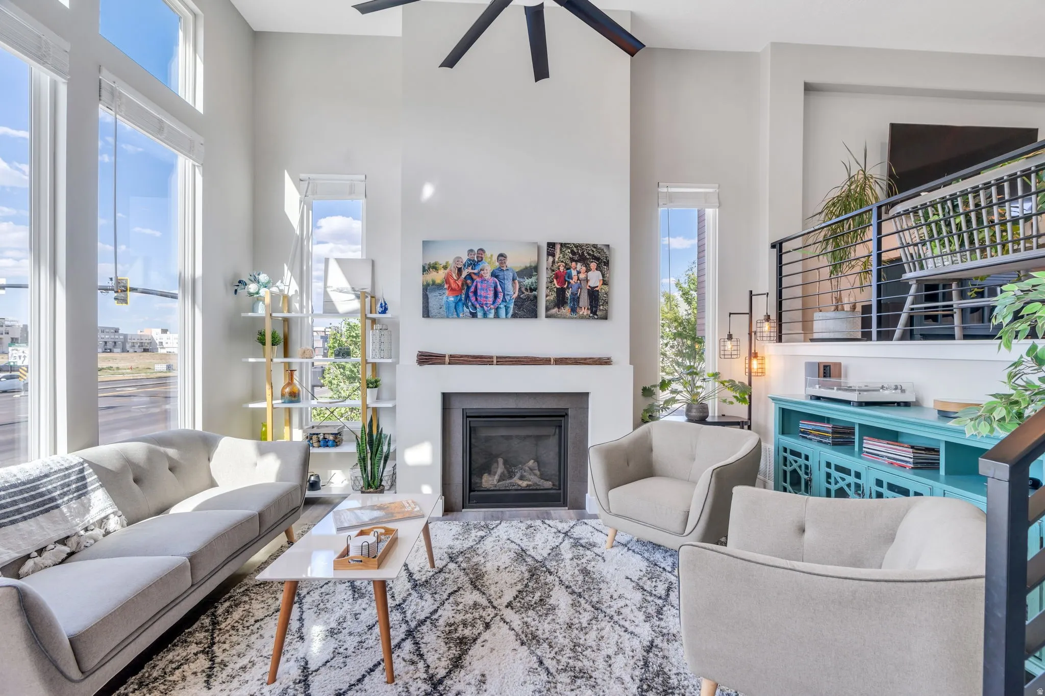 Living room featuring a high ceiling, a glass covered fireplace, and a ceiling fan