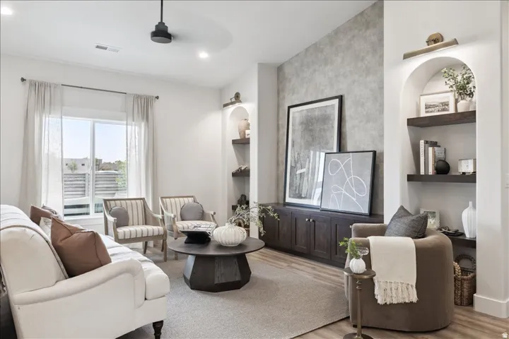 Living room with light wood finished floors, built in features, and recessed lighting