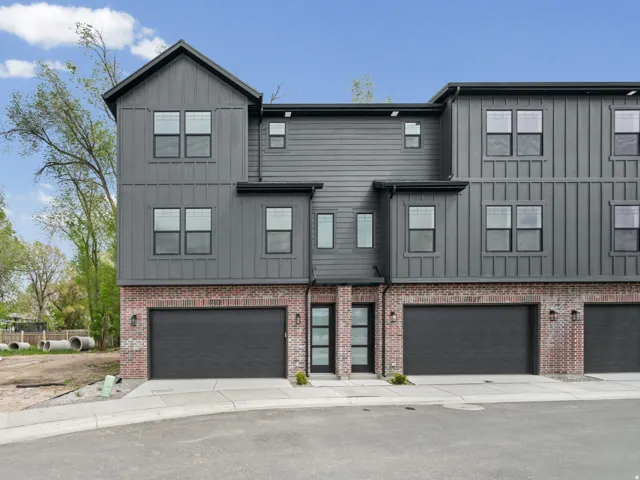 View of front of house featuring board and batten siding, an attached garage, driveway, and brick siding