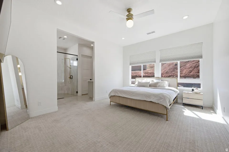 Bedroom featuring arched walkways, light carpet, a ceiling fan, ensuite bathroom, and recessed lighting