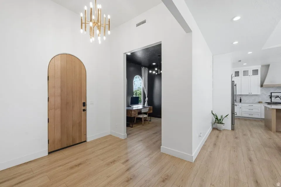 Entrance foyer with arched walkways, suspended lighting, and light wood-type flooring