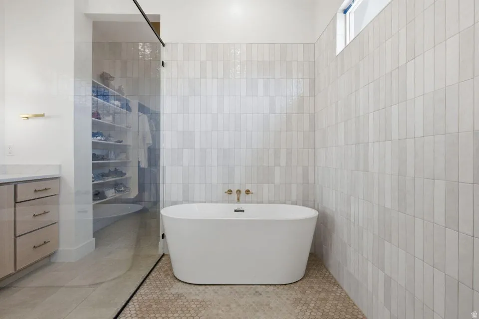 Bathroom featuring vanity, a freestanding bath, tile walls, light tile patterned floors, and a shower