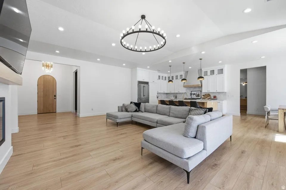 Living room featuring hanging lights, arched walkways, light wood finished floors, and a glass covered fireplace