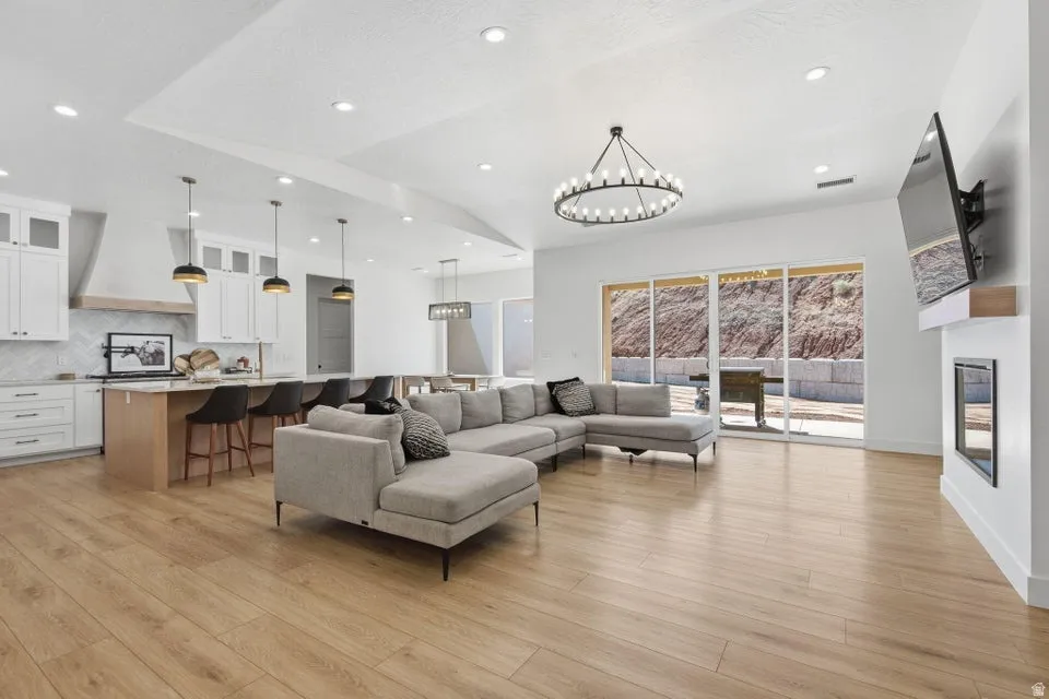 Living room featuring suspended lighting, light wood-style flooring, and a fireplace