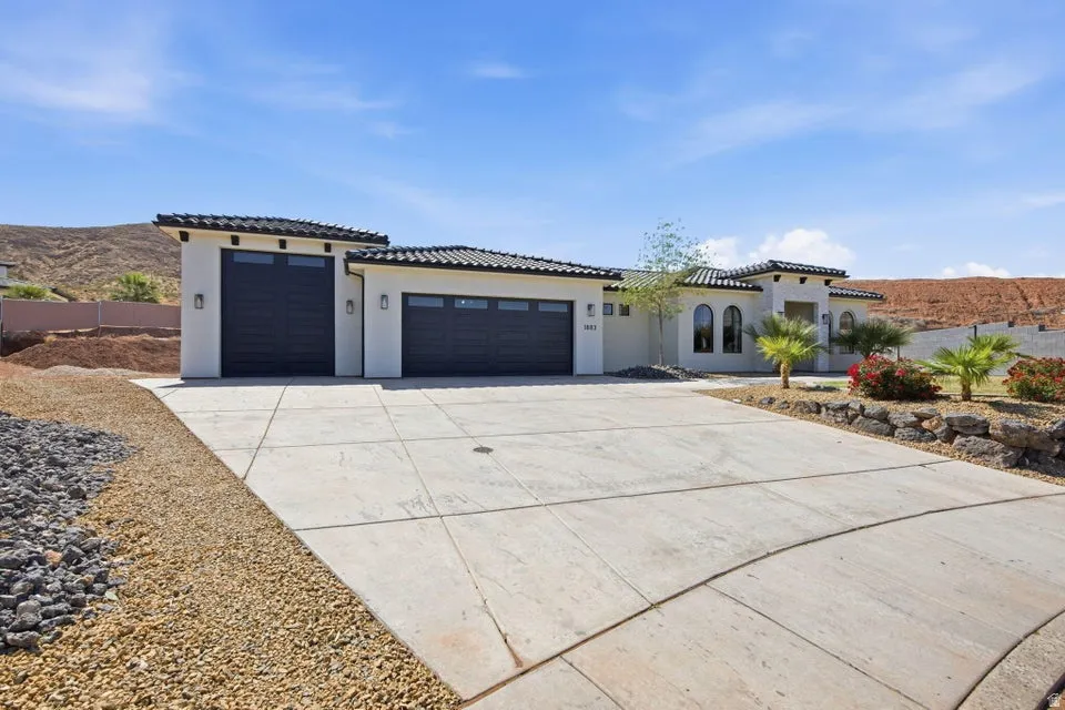 View of front of property featuring a garage, concrete driveway, stucco siding, a tiled roof, and a mountain view