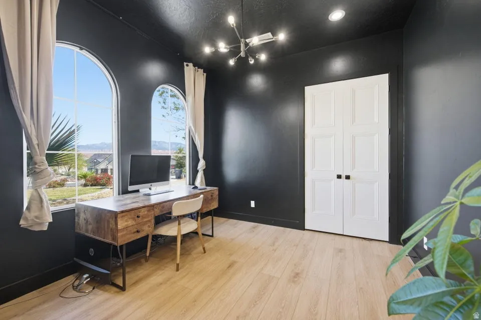 Home office with light wood-type flooring and hanging lights