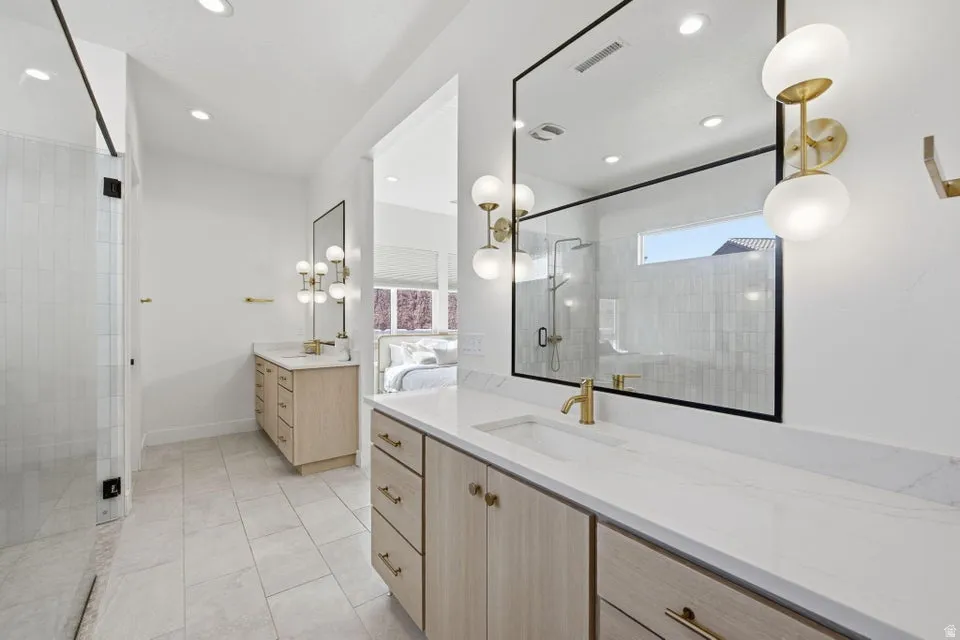 Bathroom featuring two vanities, a stall shower, light tile patterned floors, and recessed lighting