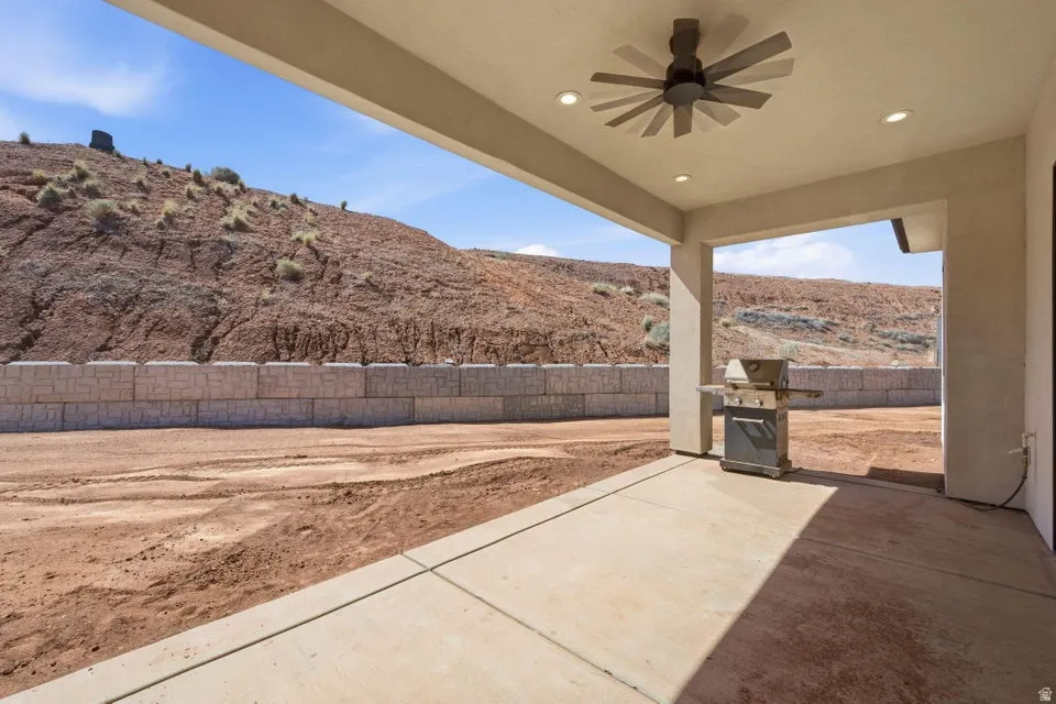 Fenced backyard with a ceiling fan, a grill, a patio area, and a mountain view