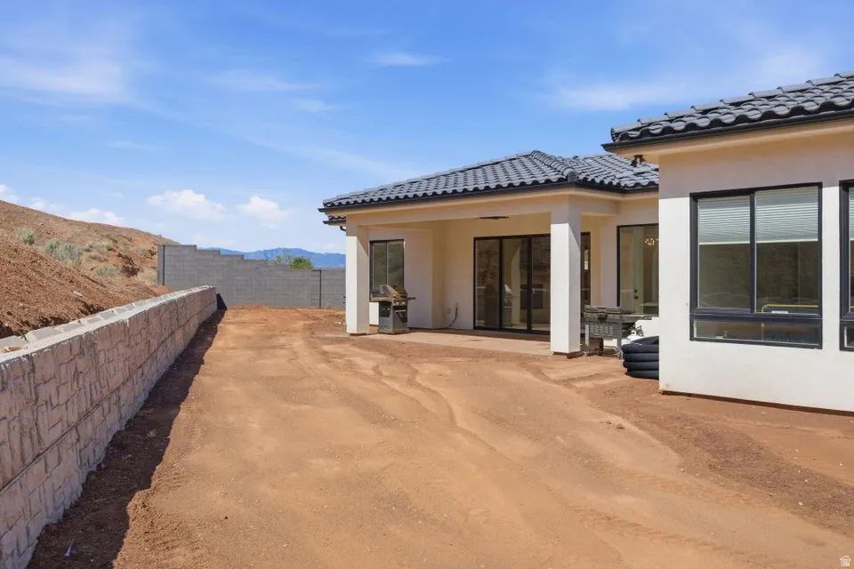 Back of house featuring a patio area, stucco siding, a mountain view, and a tile roof