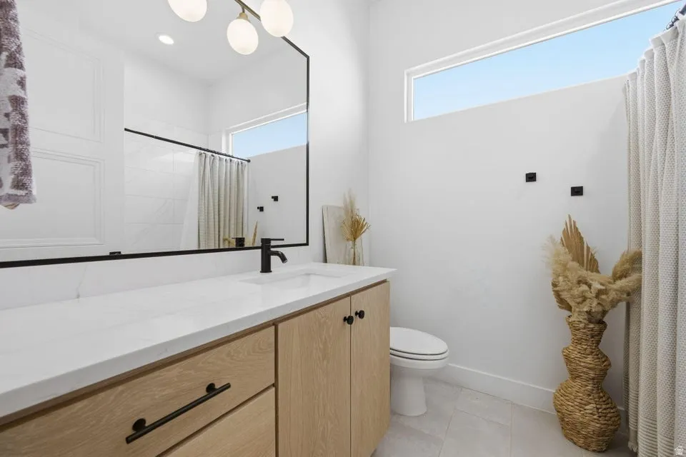 Bathroom featuring vanity, healthy amount of natural light, a shower with shower curtain, and light tile patterned flooring