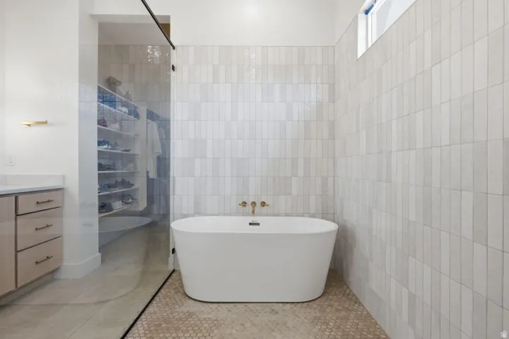 Bathroom featuring vanity, a freestanding bath, tile walls, light tile patterned floors, and a shower