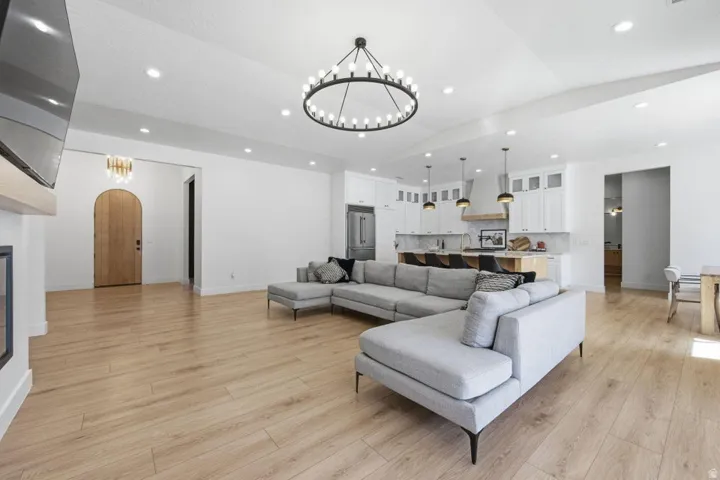 Living room featuring hanging lights, arched walkways, light wood finished floors, and a glass covered fireplace