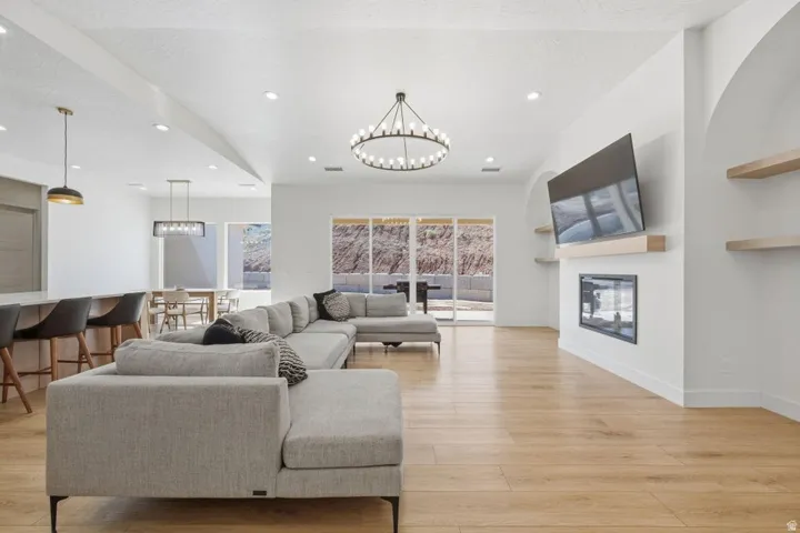 Living room featuring a glass covered fireplace, hanging lights, and light wood-style floors