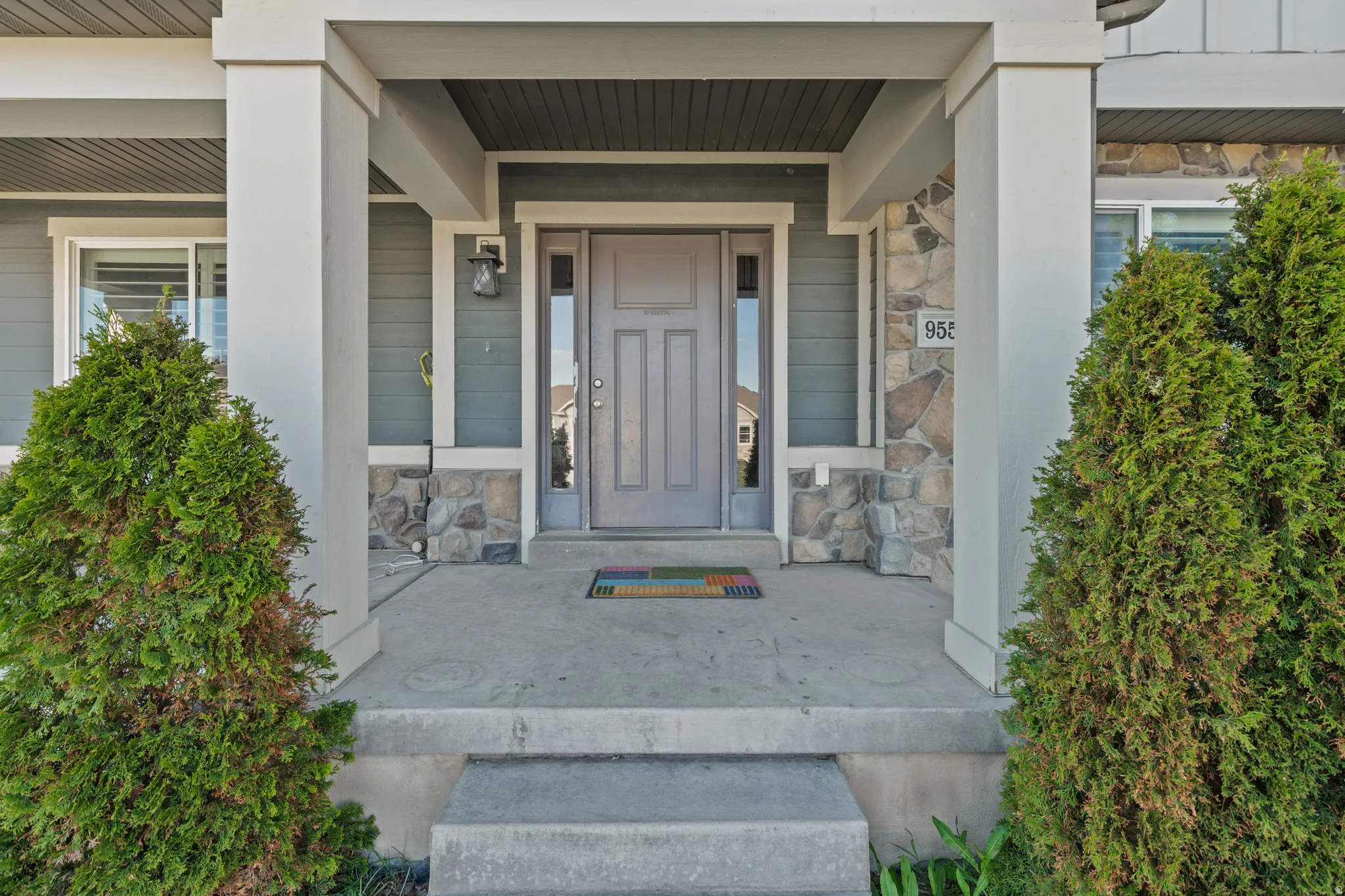 View of exterior entry with stone siding and covered porch