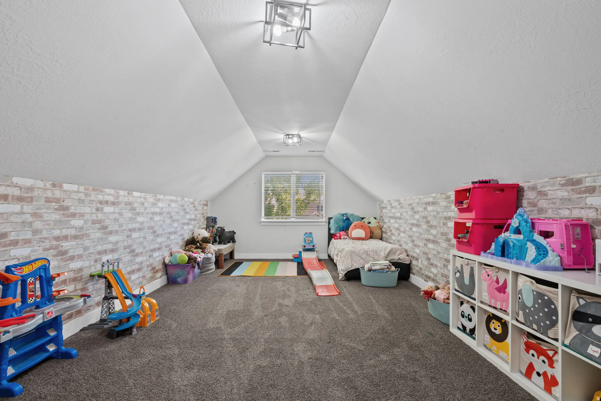 Game room with brick wall, dark carpet, and a textured ceiling