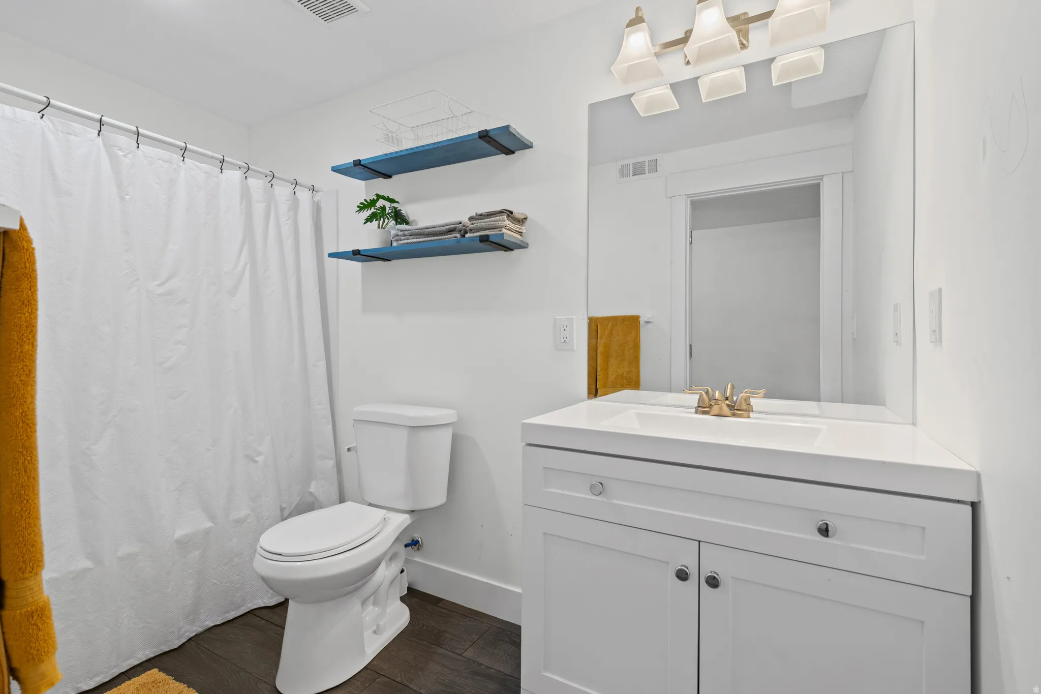 Full bath featuring vanity, dark wood-style floors, and shower / bath combo with shower curtain