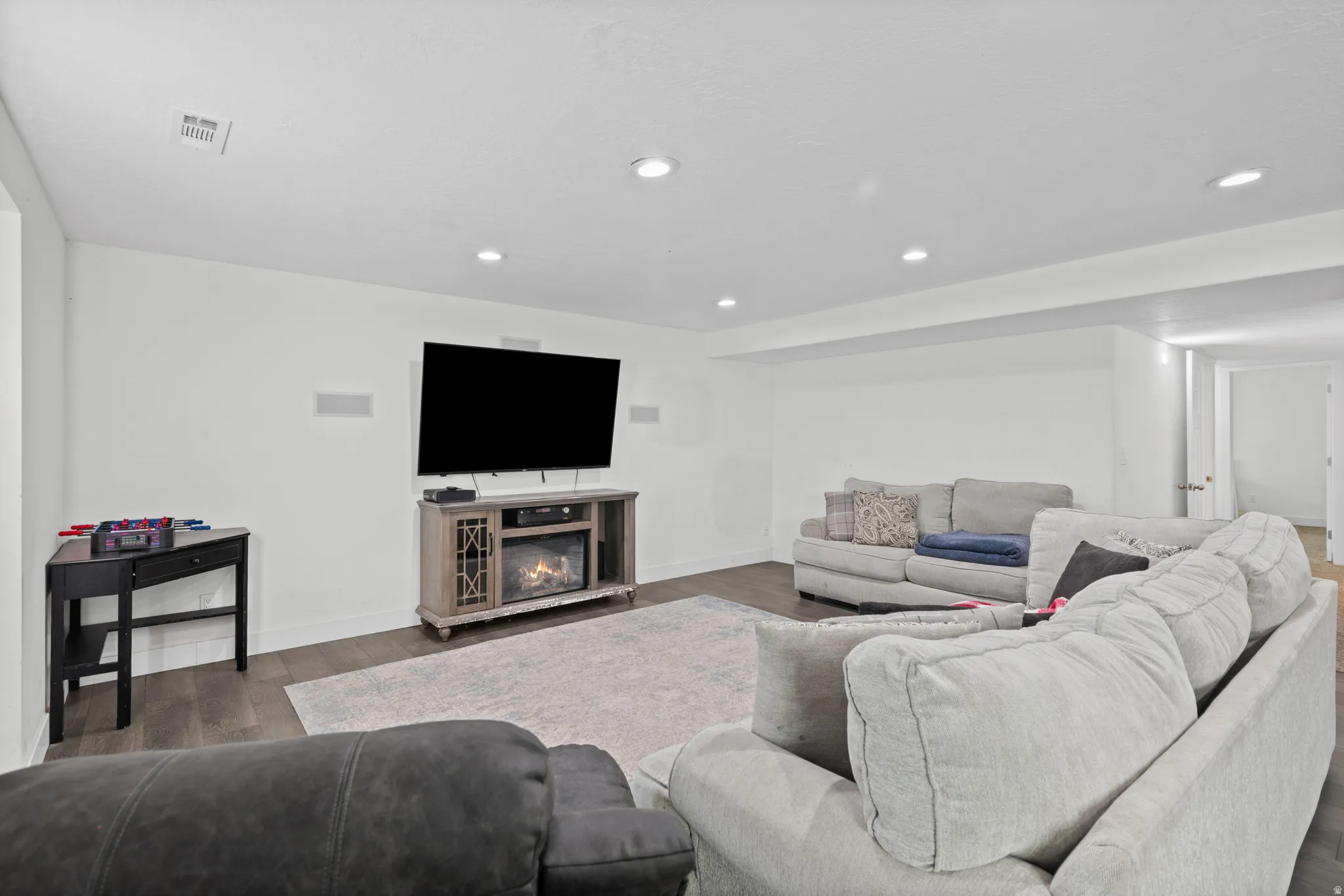 Living area featuring wood finished floors, a glass covered fireplace, and recessed lighting
