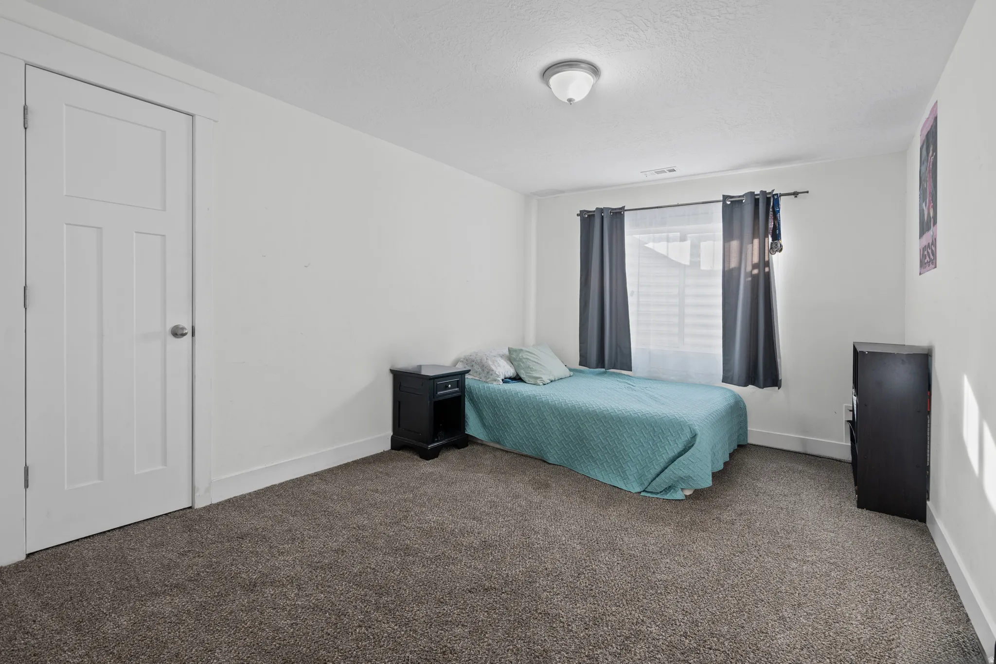 Carpeted bedroom featuring baseboards and a textured ceiling
