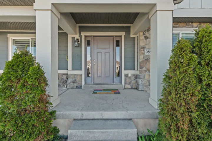 View of exterior entry with stone siding and covered porch