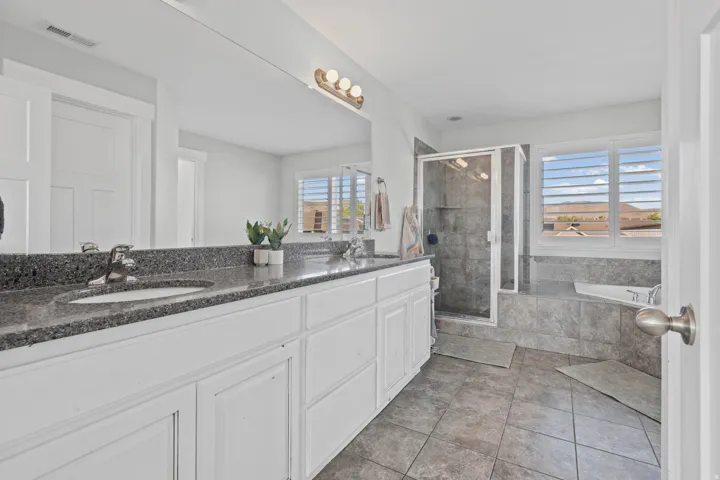 Bathroom featuring double vanity, a garden tub, a stall shower, and light tile patterned floors