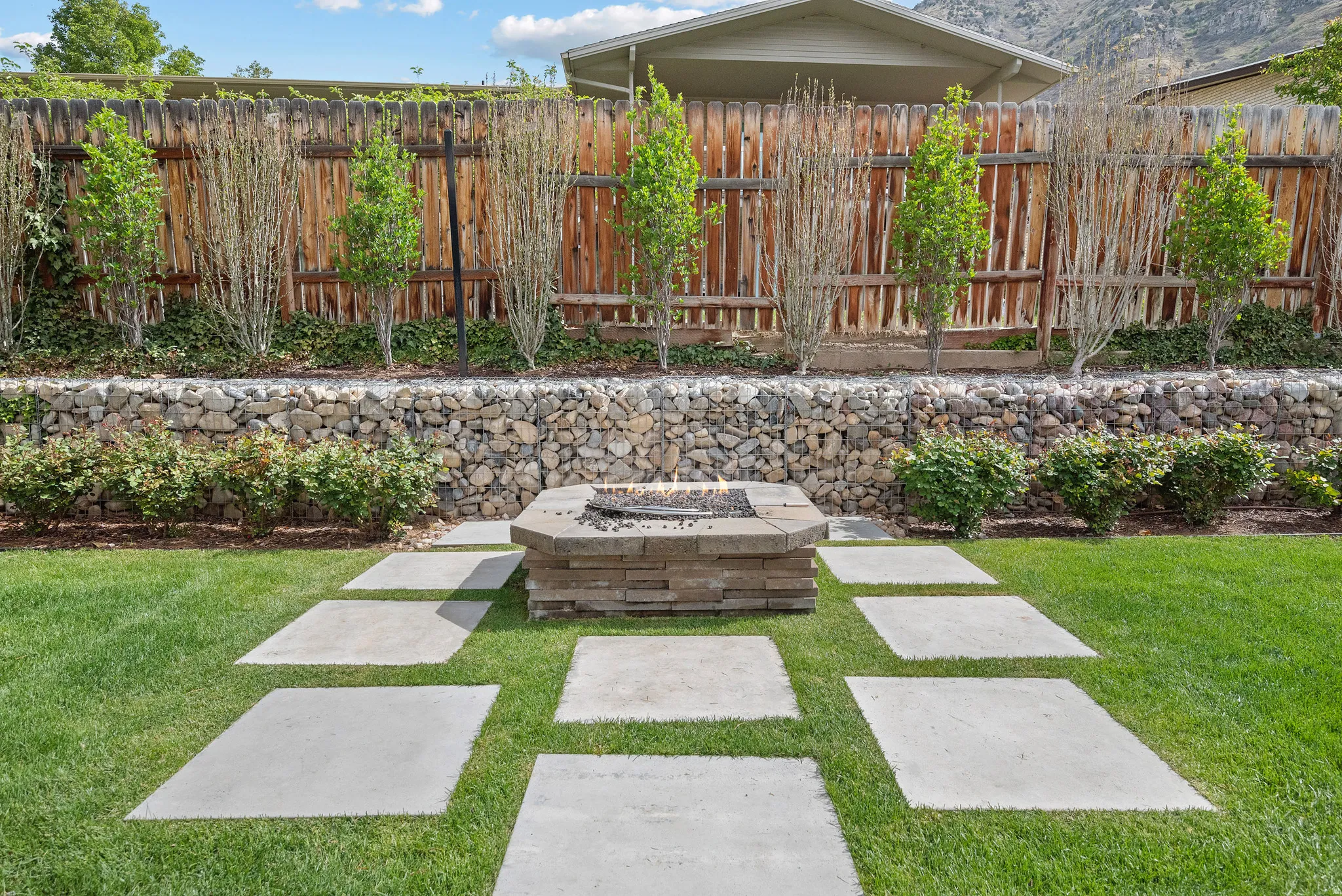 Fenced backyard with an outdoor fire pit, a patio area, and a mountain view