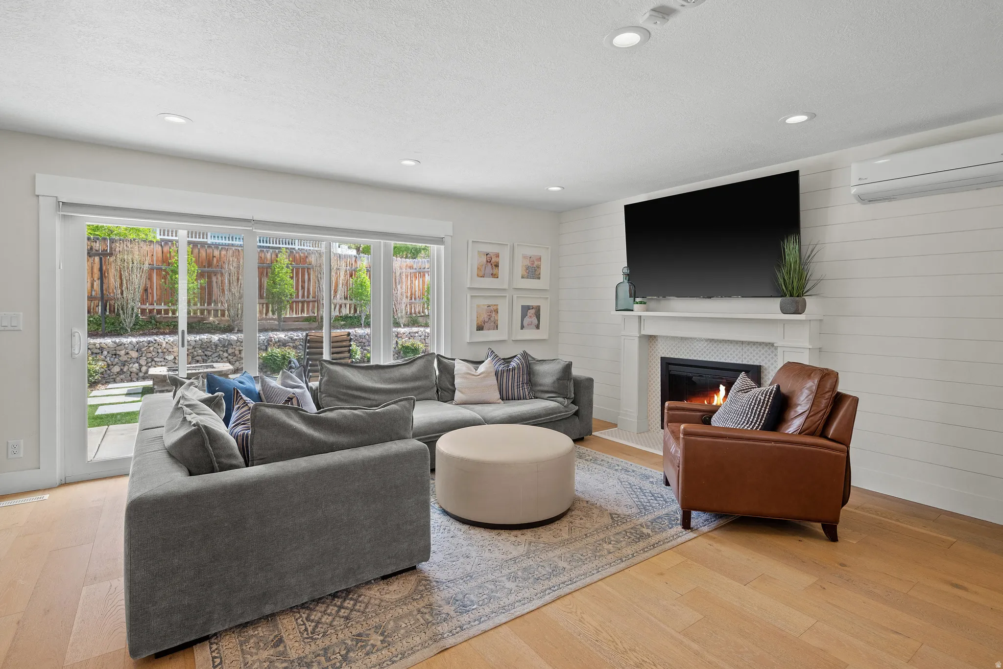 Living room with light wood-style flooring, a tiled fireplace, recessed lighting, and a textured ceiling