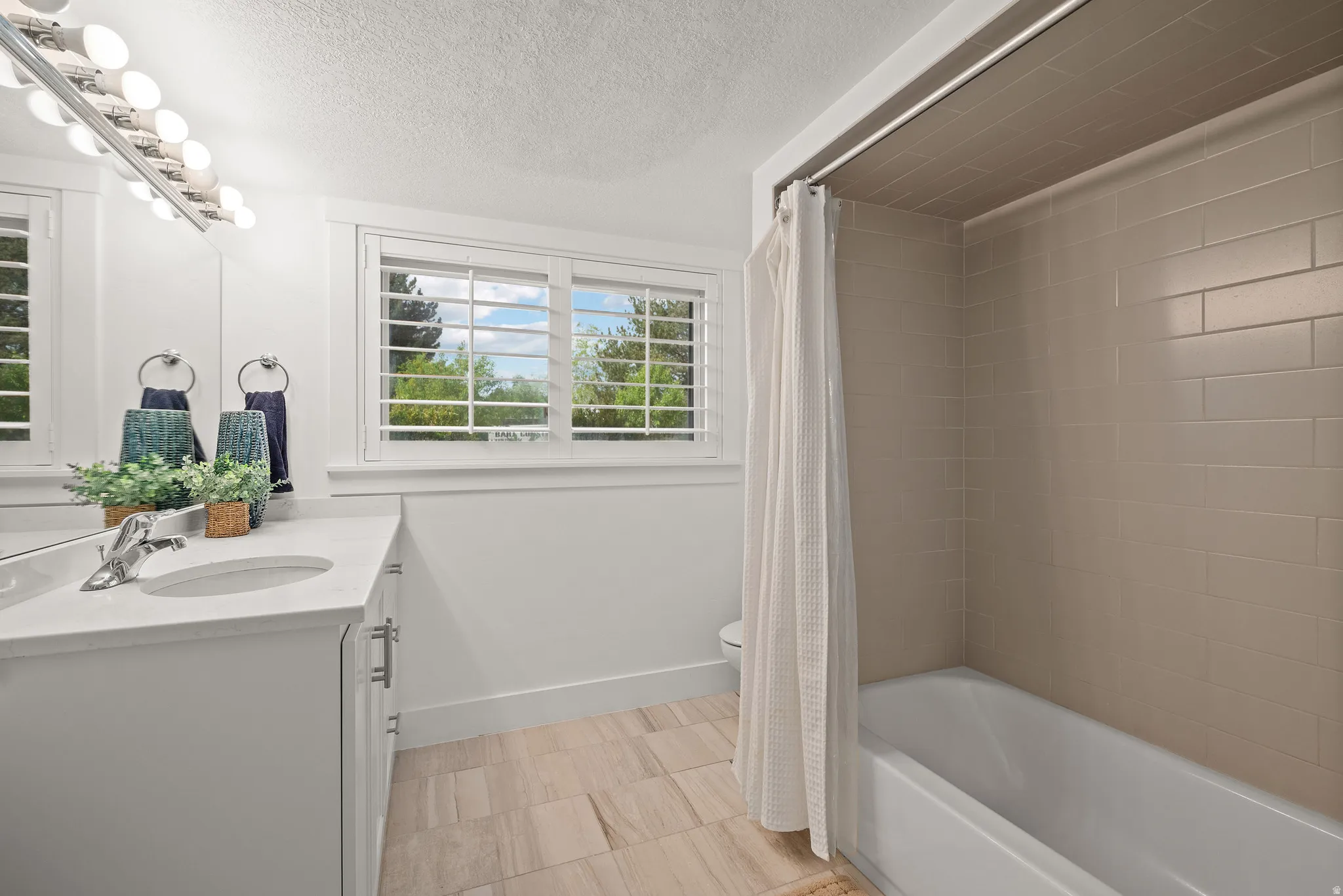 Full bath featuring vanity, shower / bath combo with shower curtain, and a textured ceiling