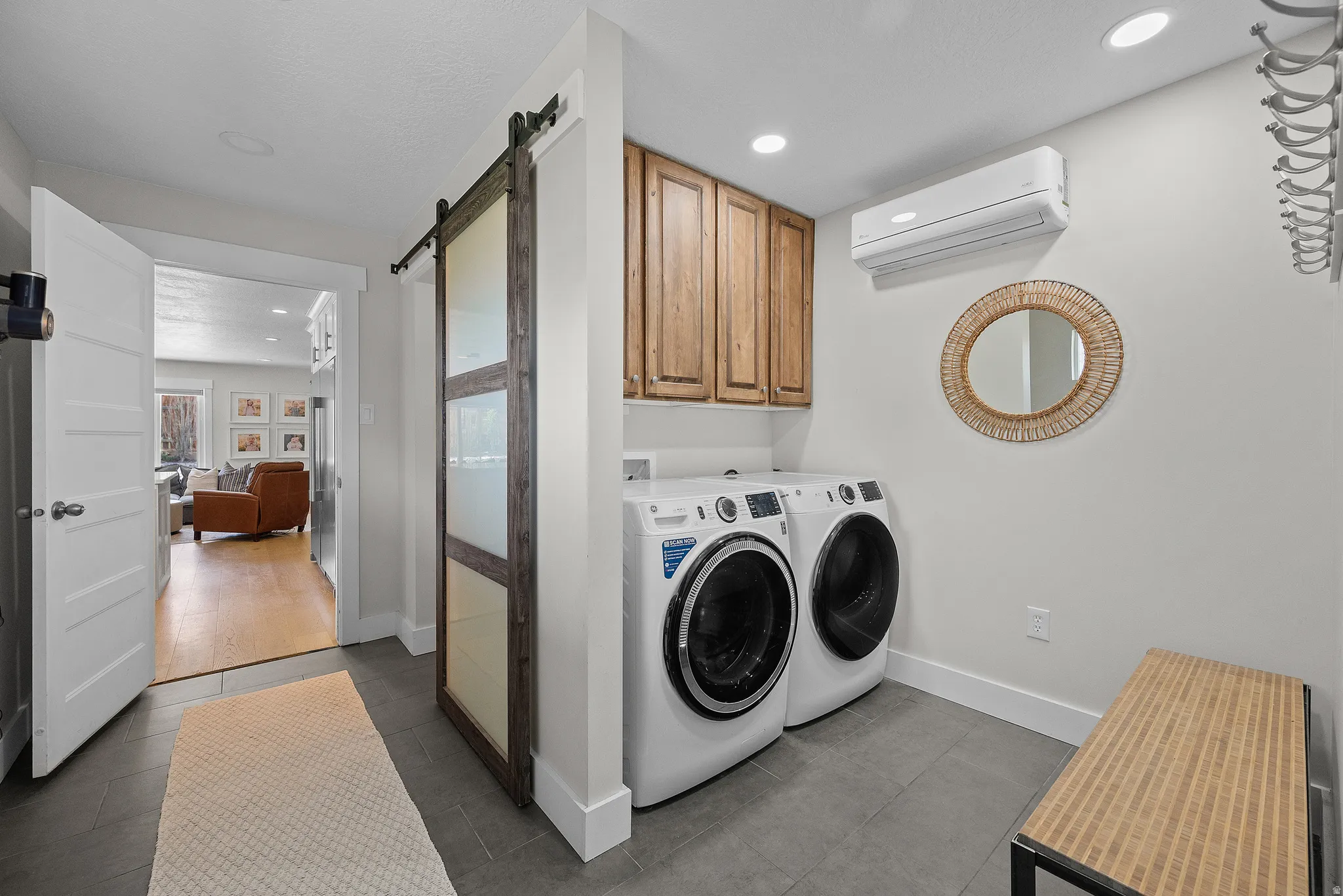 Laundry area featuring a barn door, dark tile patterned floors, independent washer and dryer, cabinet space, and recessed lighting