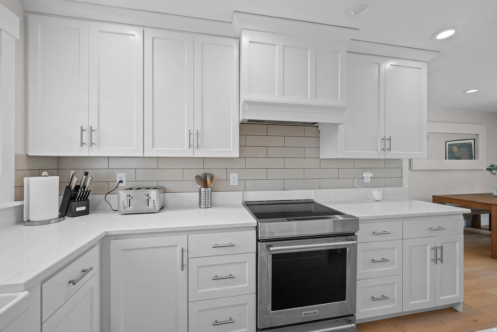 Kitchen with high end stainless steel range oven, white cabinets, tasteful backsplash, recessed lighting, and light stone counters