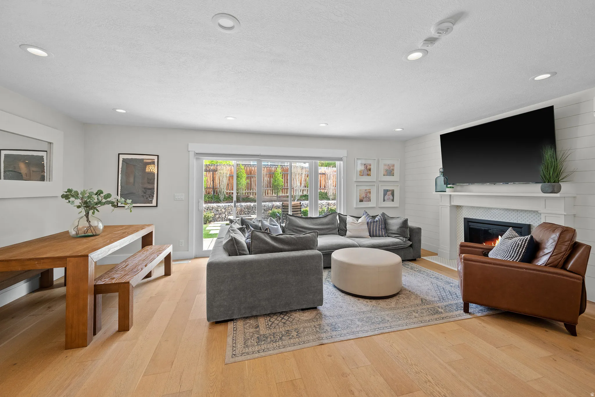 Living room with light wood-style floors, a tile fireplace, and recessed lighting