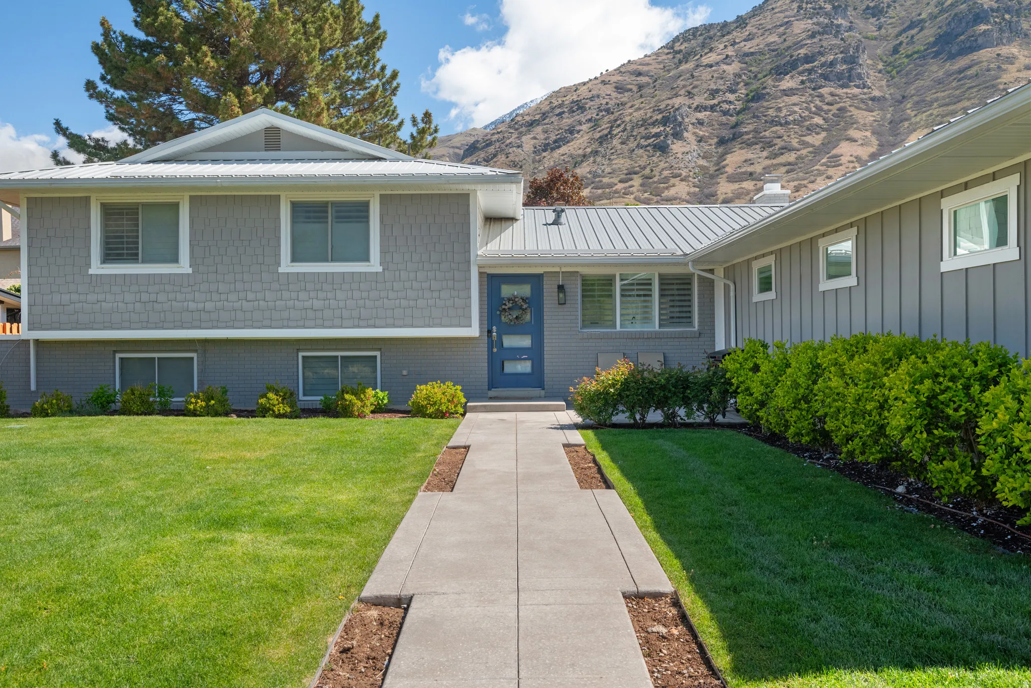Tri-level home featuring a front lawn, a metal roof, a mountain view, and board and batten siding