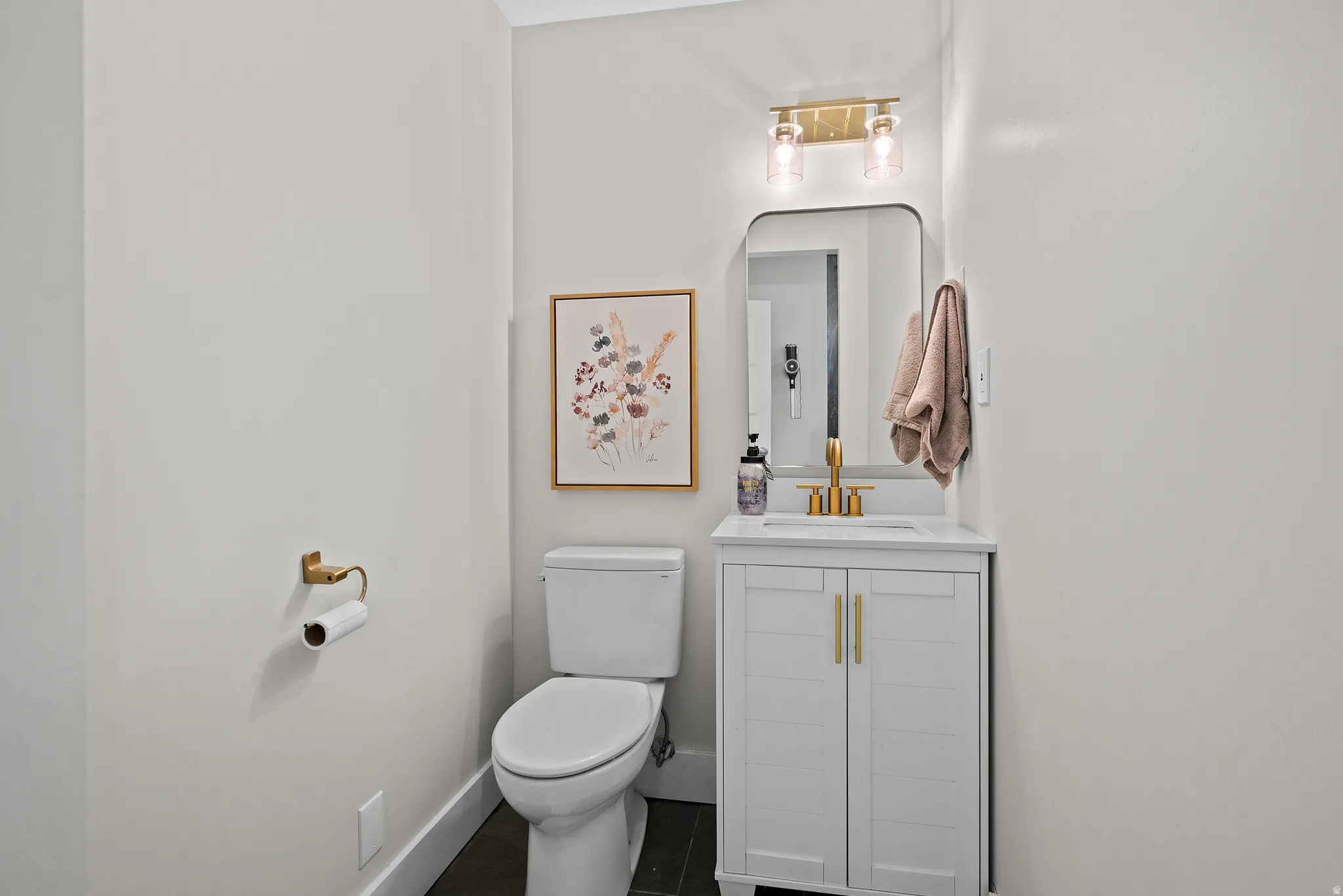 Half bath with vanity and dark tile patterned flooring
