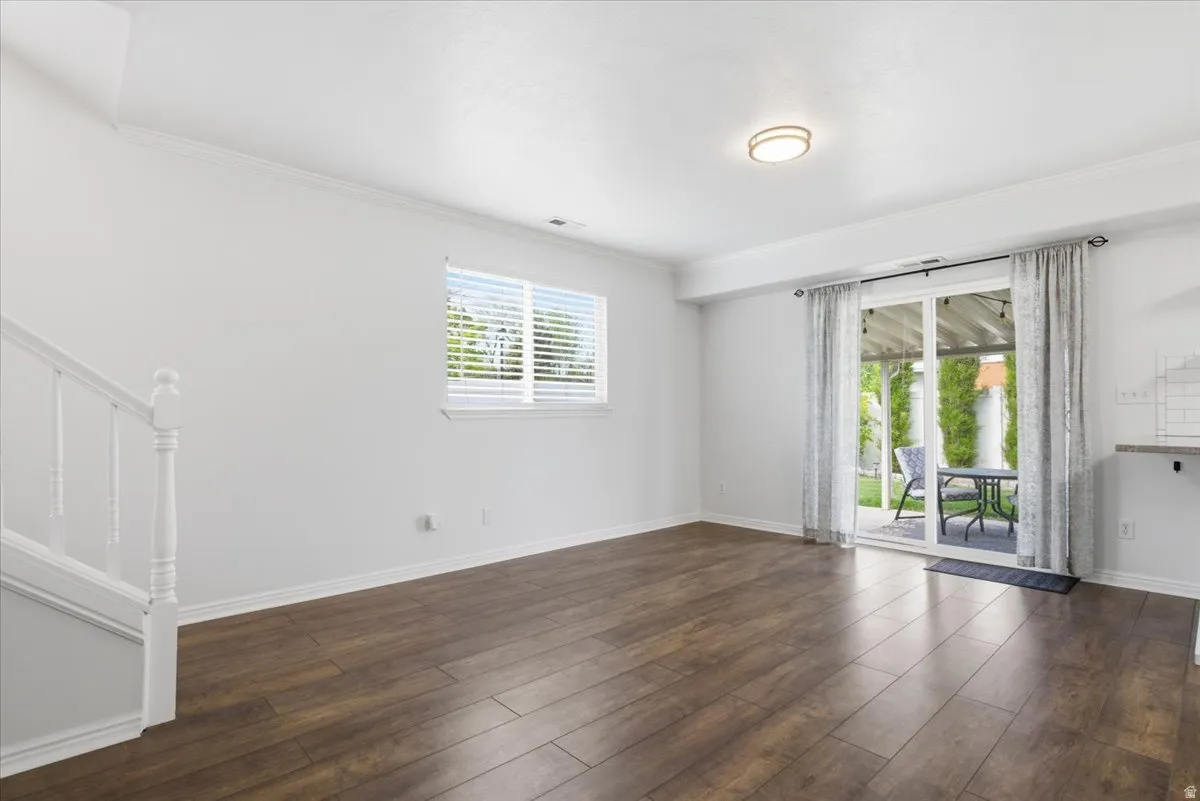 Empty room featuring dark wood finished floors and ornamental molding