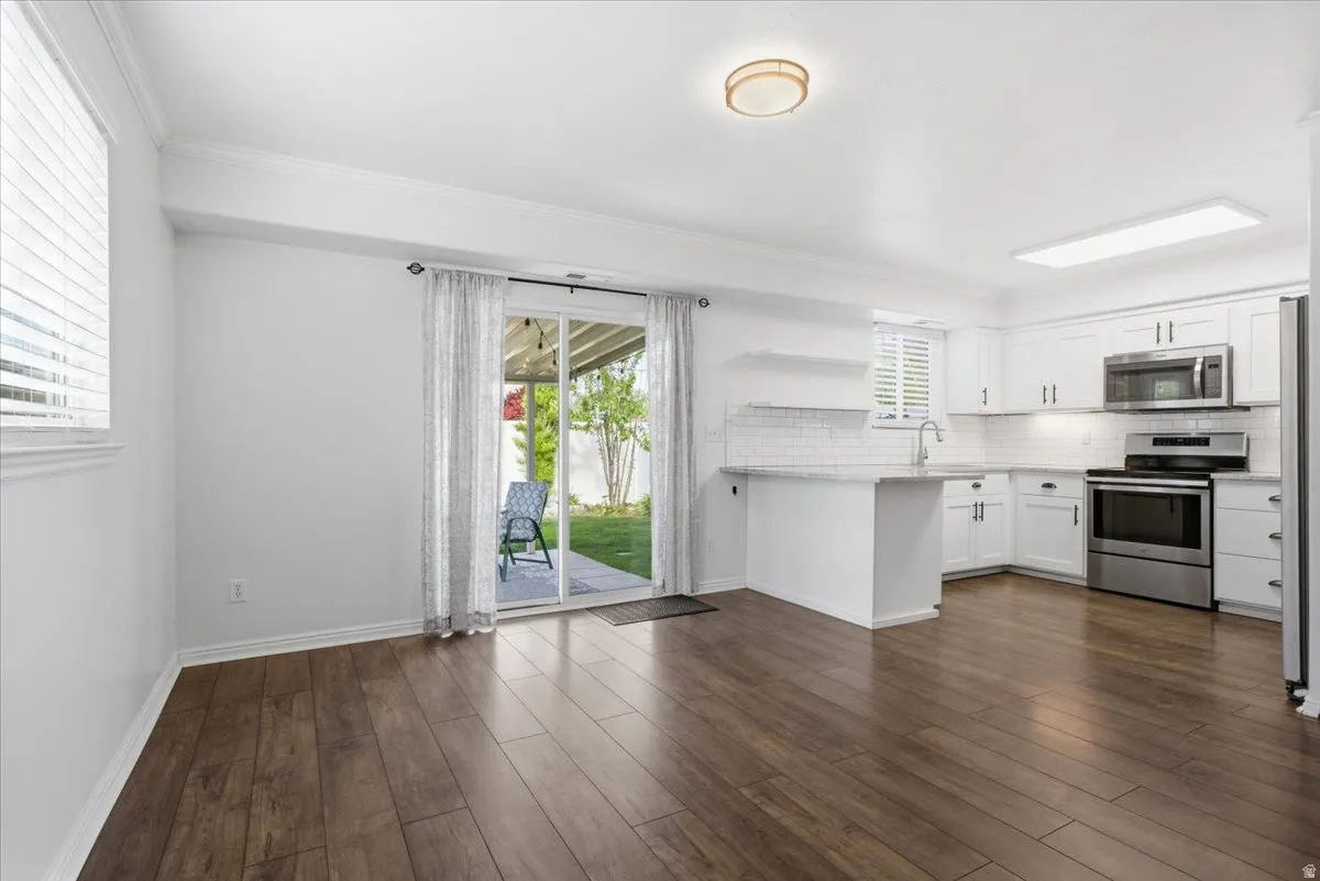 Kitchen featuring open shelves, stainless steel appliances, decorative backsplash, white cabinets, and dark wood-style floors