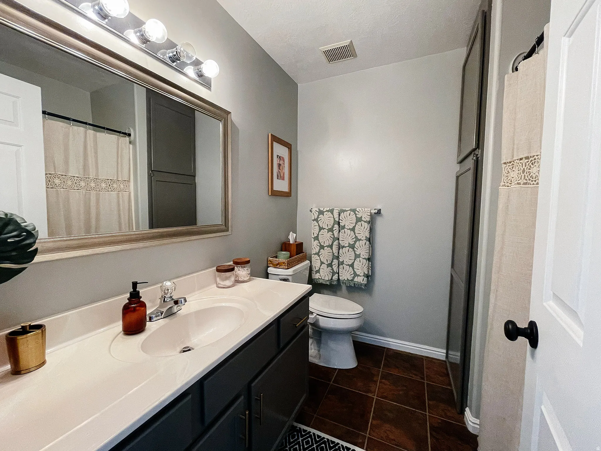 Full bathroom with vanity, a shower with shower curtain, and dark tile patterned flooring