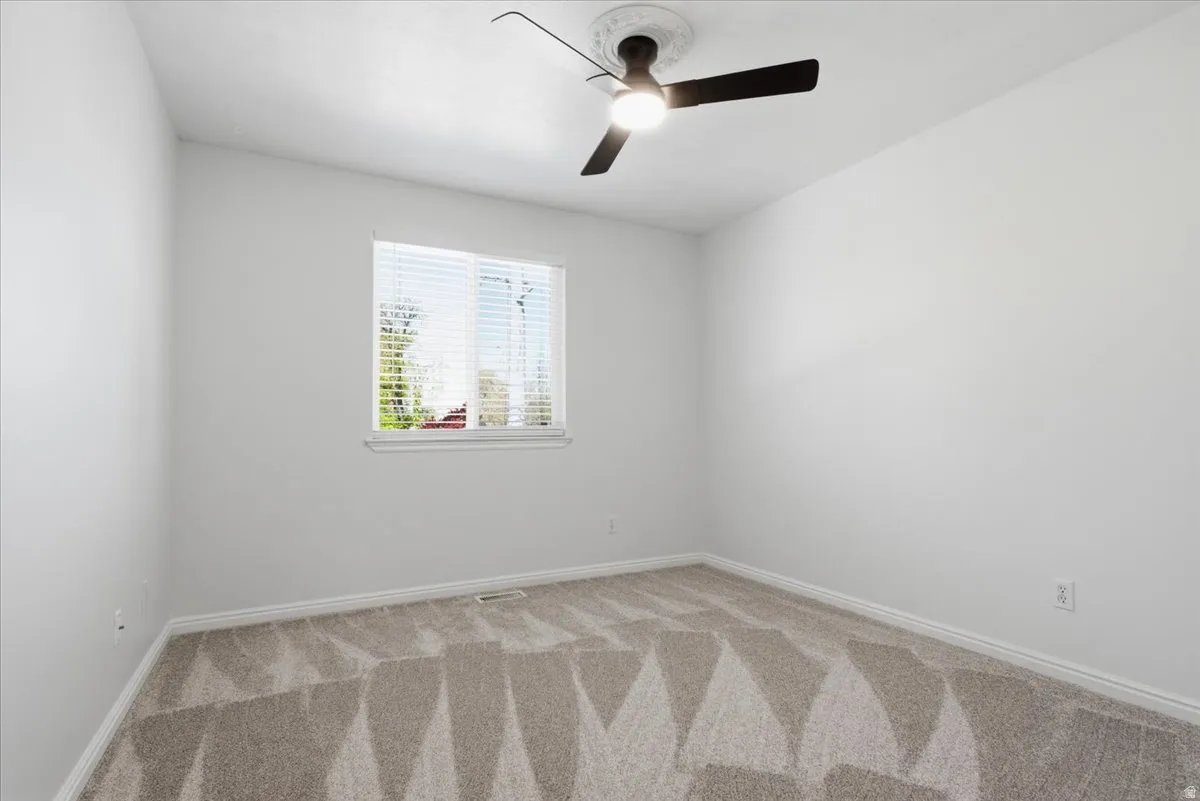 Spare room with ceiling fan and light carpet