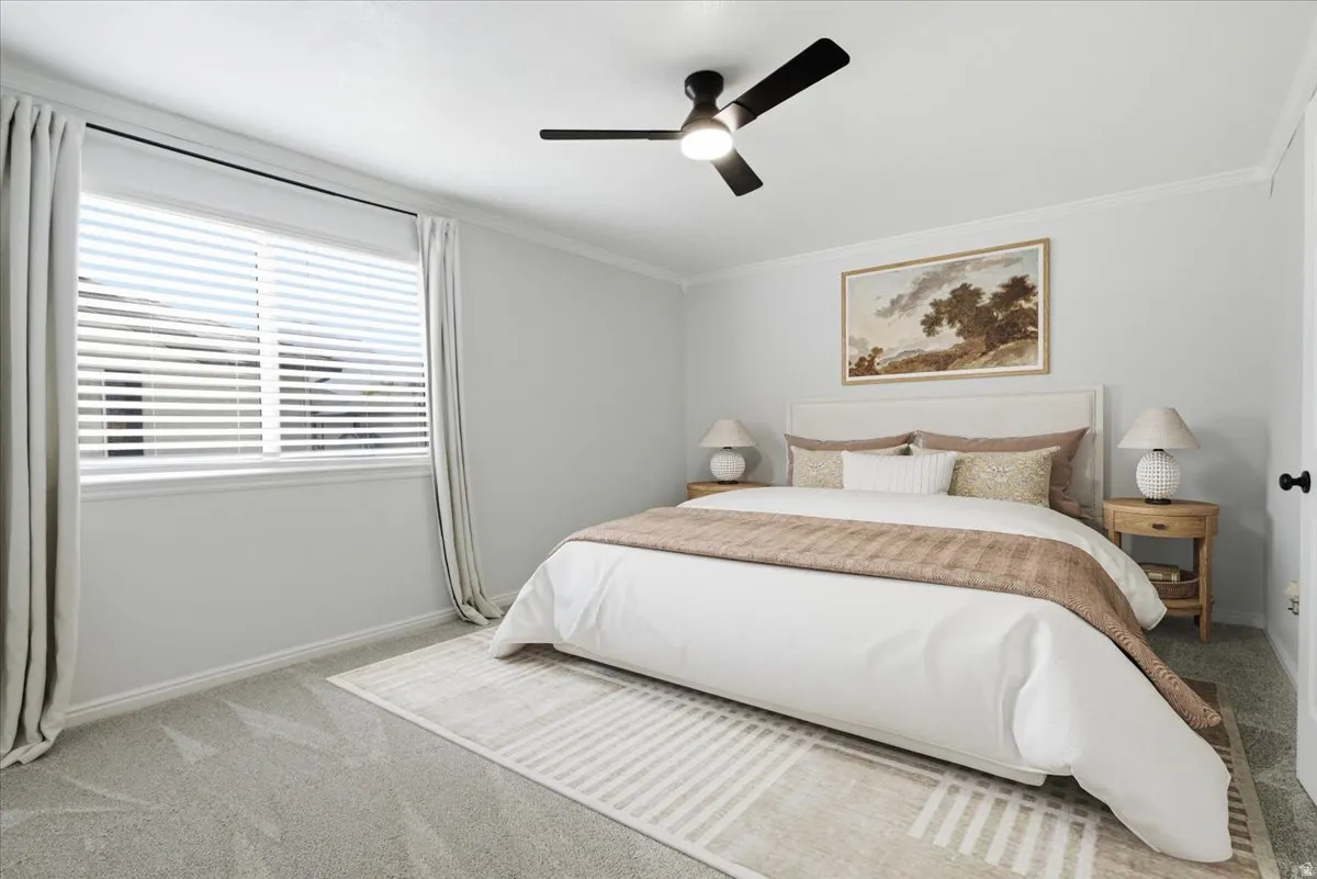 Bedroom featuring light colored carpet, a ceiling fan, and ornamental molding