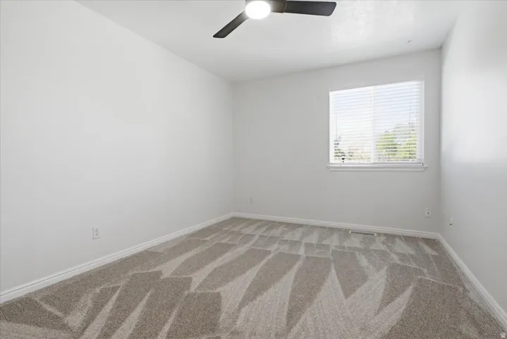 Spare room featuring light carpet and ceiling fan