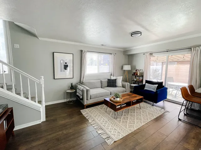 Living room featuring a textured ceiling, dark wood-style floors, and crown molding