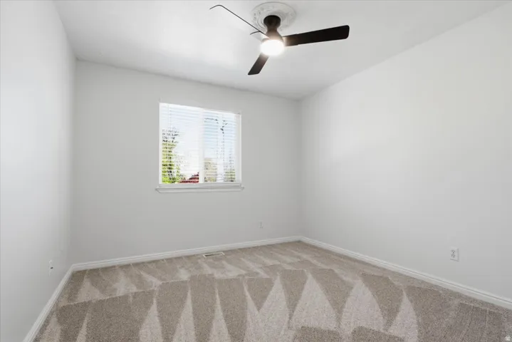 Spare room with ceiling fan and light carpet