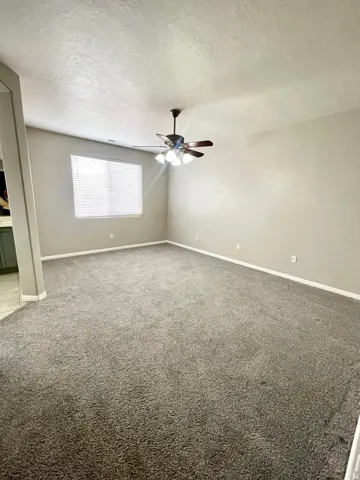 Spare room with carpet flooring, a textured ceiling, and a ceiling fan