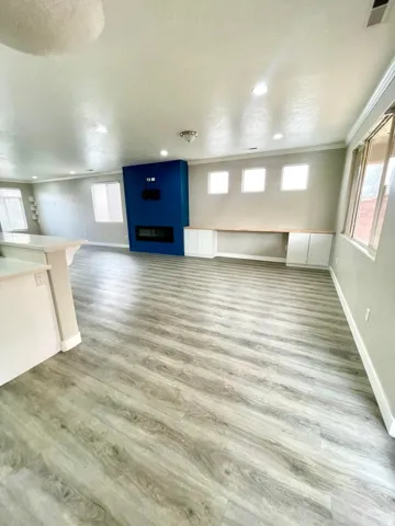 Unfurnished living room with light wood finished floors, recessed lighting, and a large fireplace