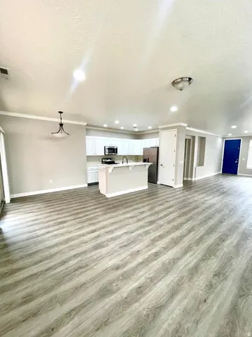Unfurnished living room featuring light wood-style floors, crown molding, and recessed lighting