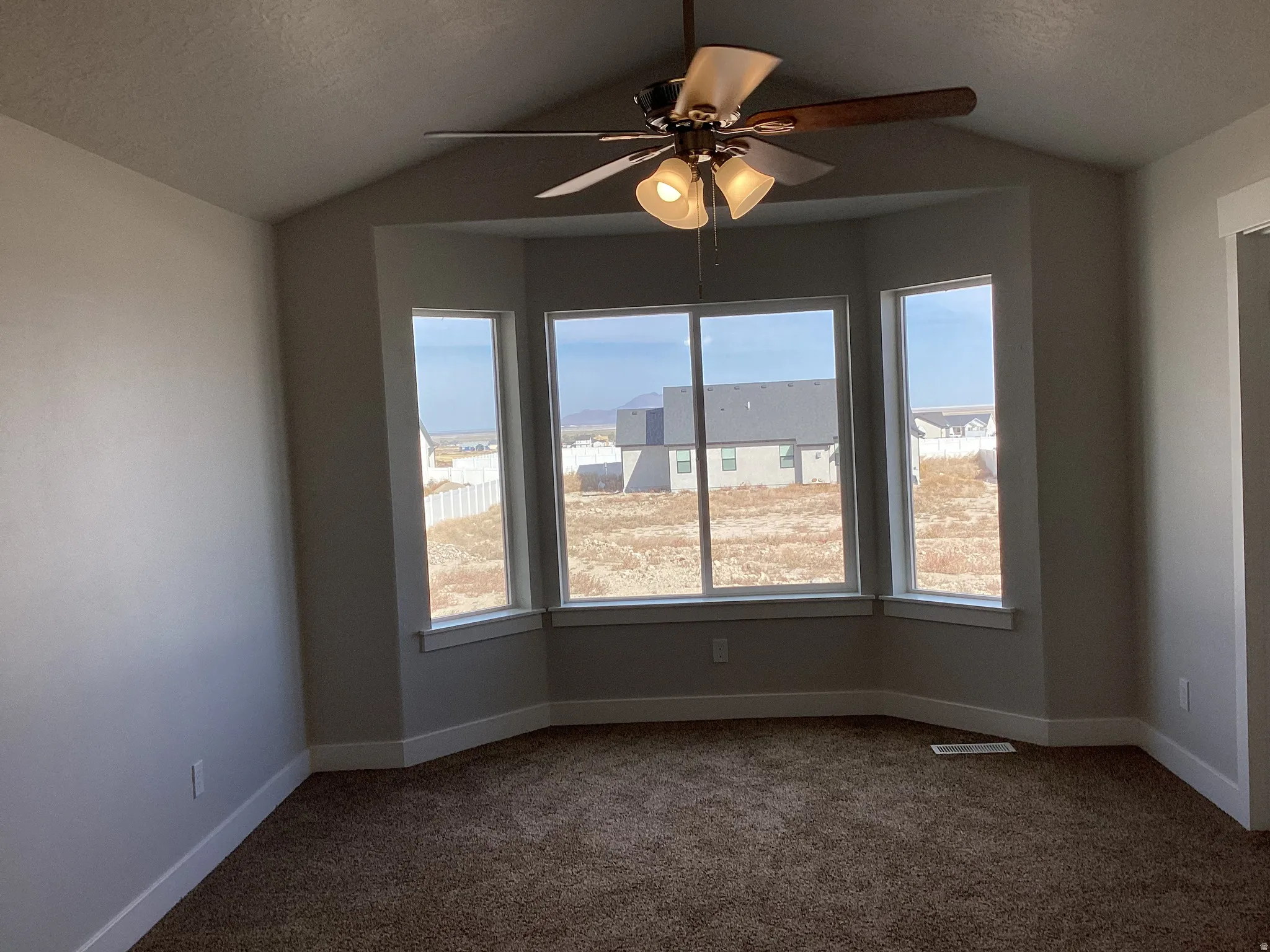 Unfurnished room featuring ceiling fan and dark colored carpet