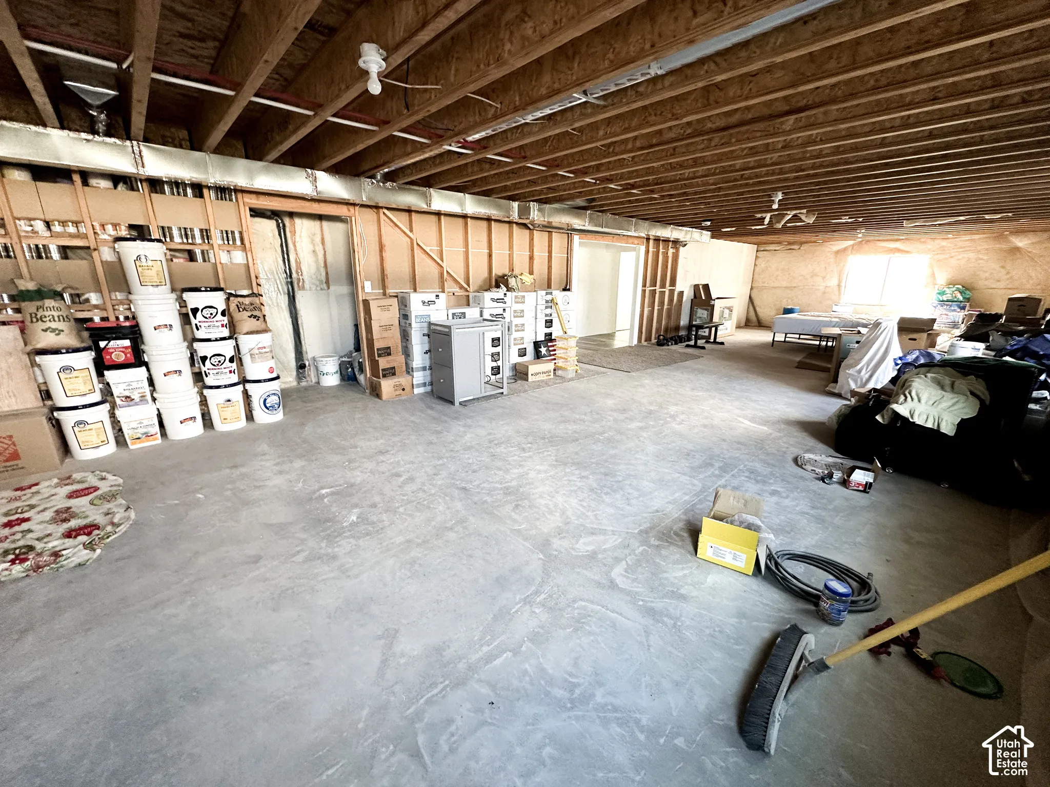 Unfinished basement with exposed ceiling joists, concrete flooring, and framing