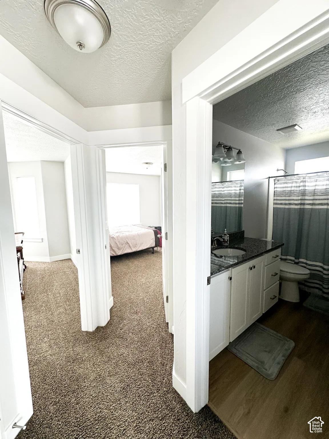 White vanity with dark countertop, undermount sink, and three-light fixture
