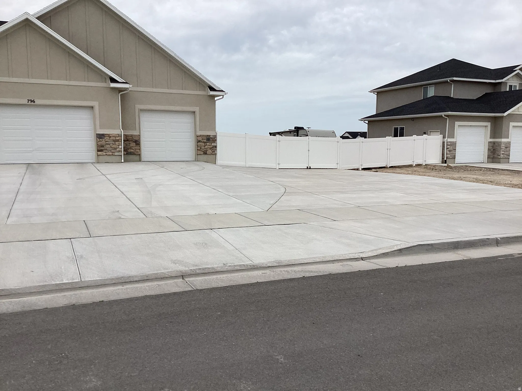 View of property exterior with stone siding, driveway, an attached garage, and stucco siding